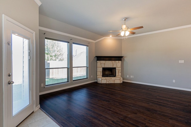 unfurnished living room with hardwood / wood-style flooring, ornamental molding, a stone fireplace, and ceiling fan