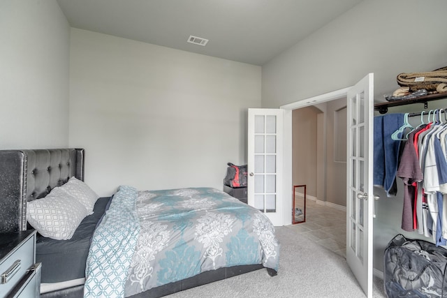 bedroom with a closet, light colored carpet, and french doors