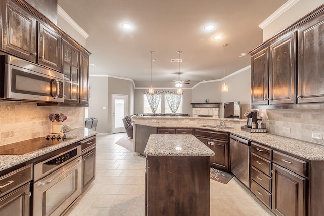 kitchen featuring a kitchen island, sink, ornamental molding, light stone counters, and stainless steel appliances