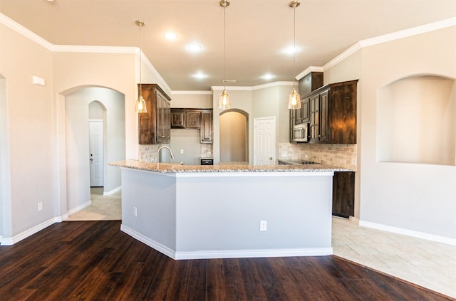 kitchen with decorative light fixtures, dark brown cabinets, light stone countertops, and dark hardwood / wood-style floors