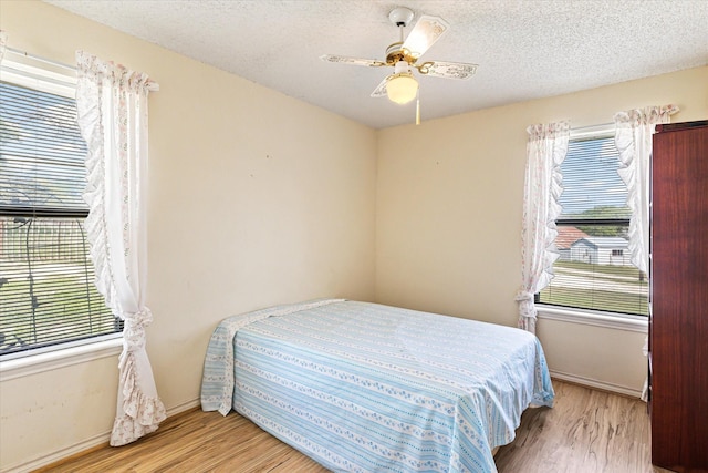 bedroom featuring ceiling fan, light hardwood / wood-style floors, and a textured ceiling