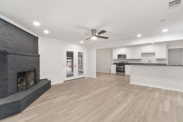 unfurnished living room featuring ceiling fan, french doors, crown molding, light hardwood / wood-style floors, and a fireplace