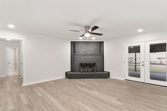 unfurnished living room featuring ceiling fan, french doors, light hardwood / wood-style flooring, crown molding, and a fireplace