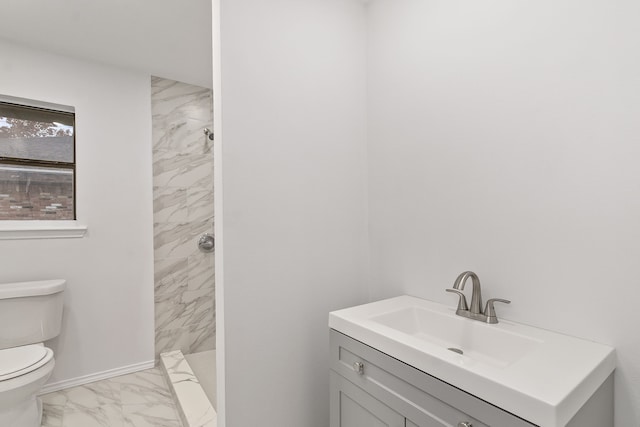 bathroom with vanity, toilet, and tiled shower