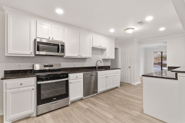 kitchen featuring white cabinets, light wood-type flooring, crown molding, and appliances with stainless steel finishes