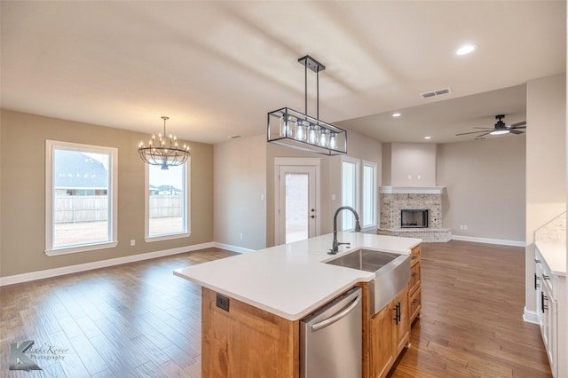 kitchen with decorative light fixtures, white cabinetry, an island with sink, dishwasher, and sink