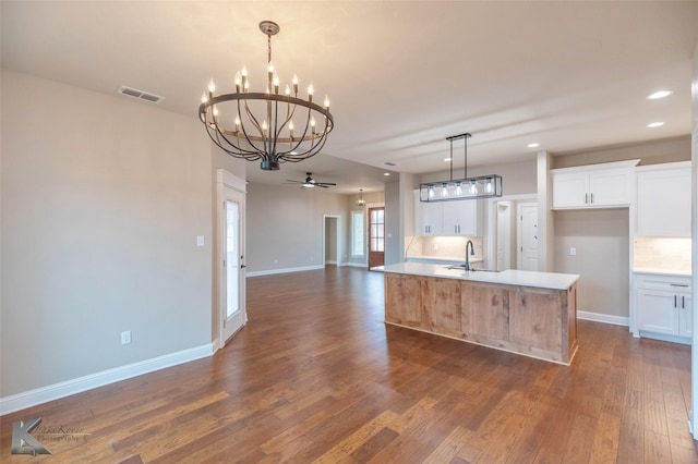 kitchen with white cabinetry, a center island with sink, and decorative backsplash