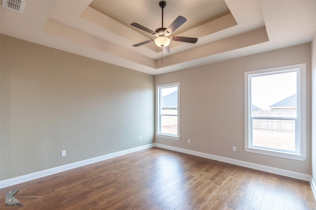 unfurnished room featuring hardwood / wood-style flooring, ceiling fan, and a tray ceiling