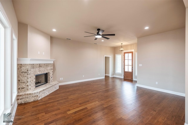 unfurnished living room with dark hardwood / wood-style flooring, a brick fireplace, and ceiling fan