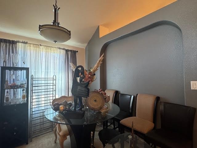 dining space featuring carpet and lofted ceiling