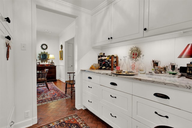 bar featuring white cabinetry, crown molding, and light stone countertops