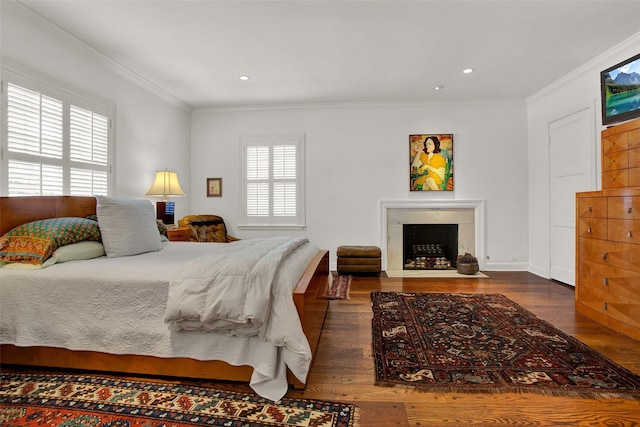 bedroom with multiple windows, a fireplace, dark wood-type flooring, and ornamental molding