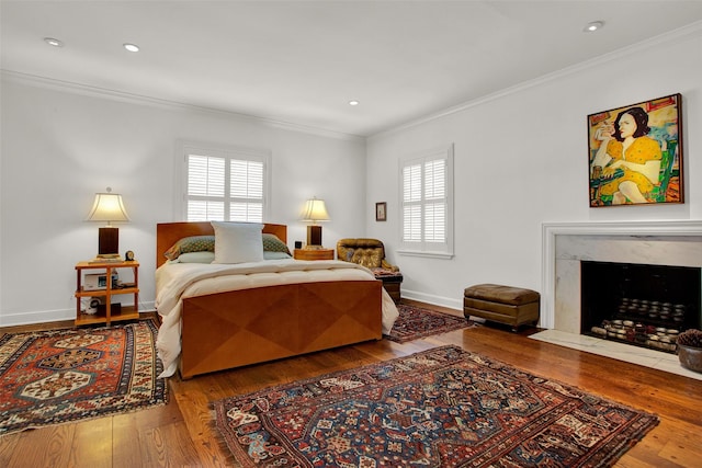 bedroom with wood-type flooring, multiple windows, crown molding, and a premium fireplace