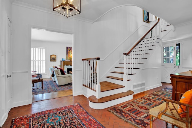 staircase with a chandelier and ornamental molding