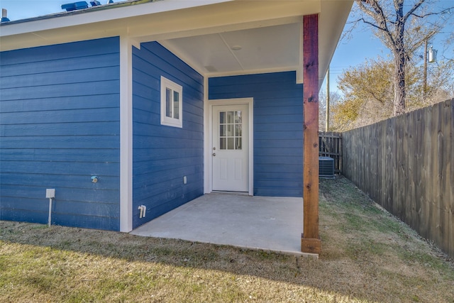 property entrance featuring a lawn, cooling unit, and a patio area