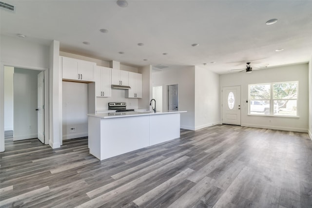 kitchen with white cabinetry, sink, wood-type flooring, stainless steel electric stove, and a center island with sink