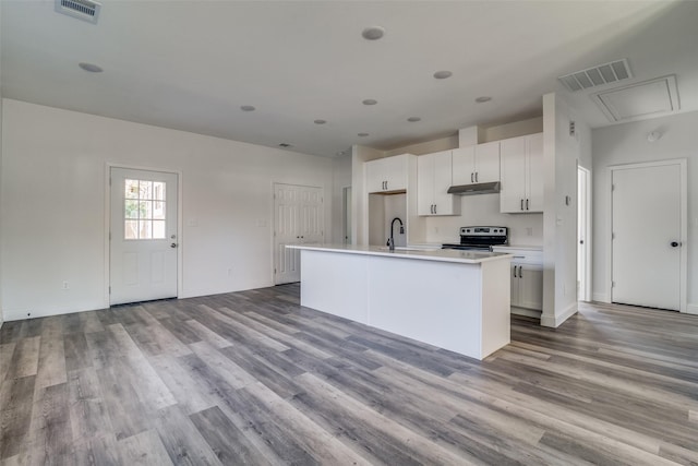 kitchen featuring white cabinetry, sink, an island with sink, stainless steel range with electric cooktop, and light wood-type flooring