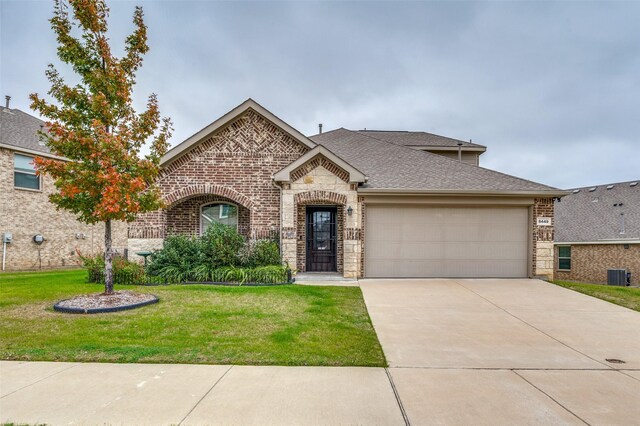 view of front of house featuring central AC unit, a garage, and a front lawn