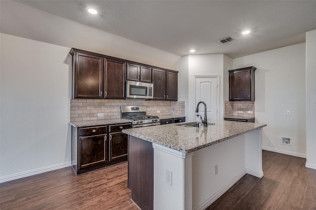 kitchen with decorative backsplash, dark hardwood / wood-style flooring, stainless steel appliances, a kitchen island with sink, and sink