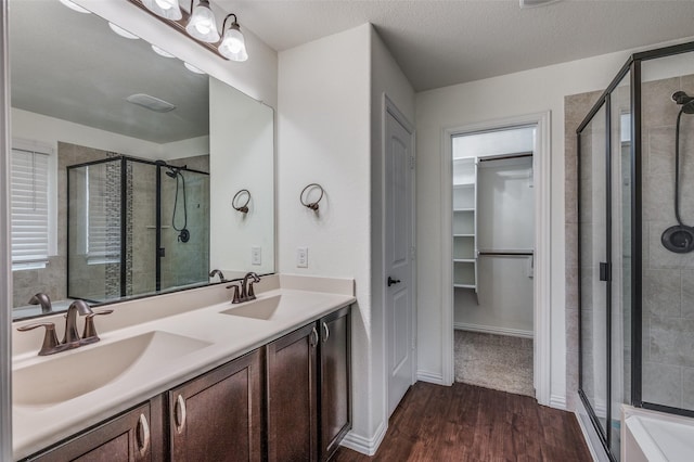 bathroom featuring hardwood / wood-style floors, vanity, a shower with shower door, and a textured ceiling