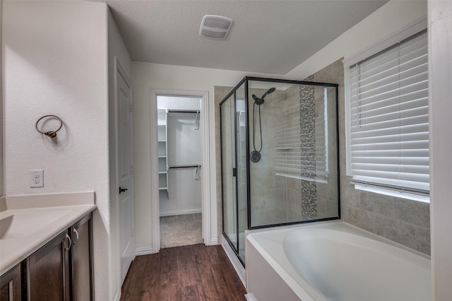 bathroom with plus walk in shower, hardwood / wood-style floors, vanity, and a textured ceiling