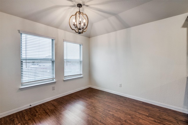 empty room featuring dark hardwood / wood-style floors, an inviting chandelier, and vaulted ceiling