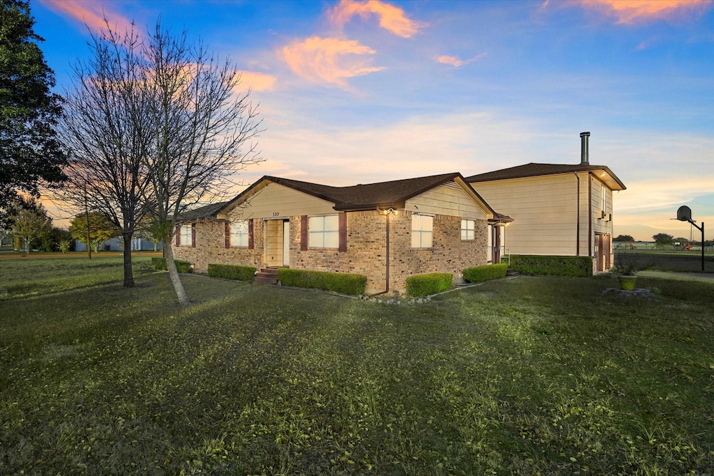 property exterior at dusk with a lawn