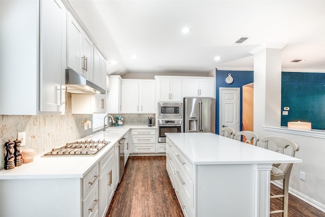 kitchen featuring a kitchen bar, white cabinets, dark wood-type flooring, and appliances with stainless steel finishes