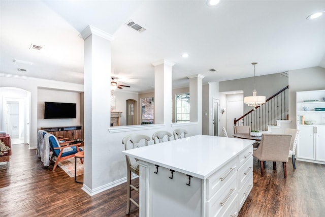 kitchen with ceiling fan, dark wood-type flooring, decorative light fixtures, white cabinets, and a center island