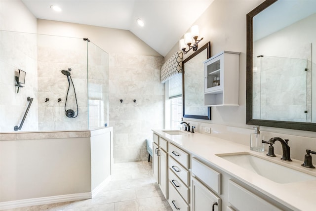 bathroom with tile patterned floors, vanity, lofted ceiling, and tiled shower