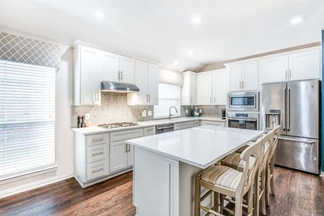 kitchen featuring appliances with stainless steel finishes, a center island, dark hardwood / wood-style floors, white cabinetry, and lofted ceiling