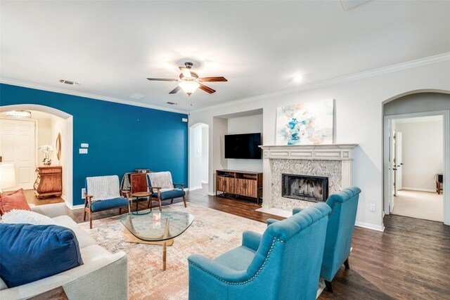 living room with ceiling fan, ornamental molding, dark wood-type flooring, and a high end fireplace