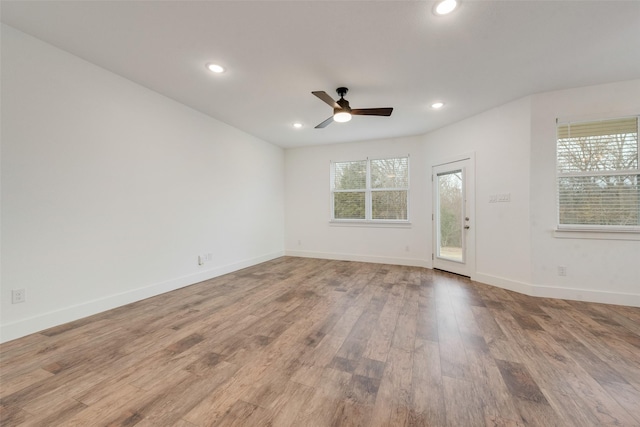 empty room featuring ceiling fan, a healthy amount of sunlight, and light wood-type flooring