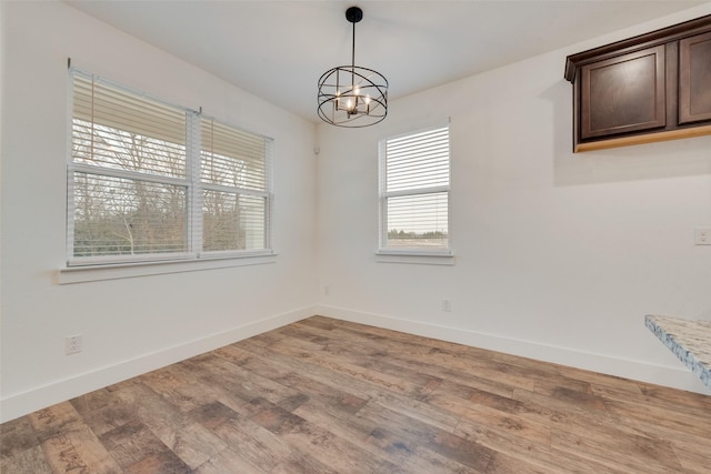 unfurnished room with wood-type flooring and an inviting chandelier