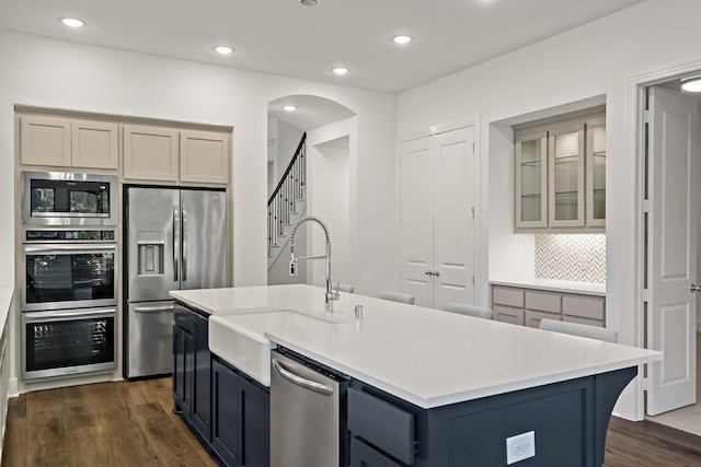 kitchen featuring gray cabinetry, a center island with sink, stainless steel appliances, and sink