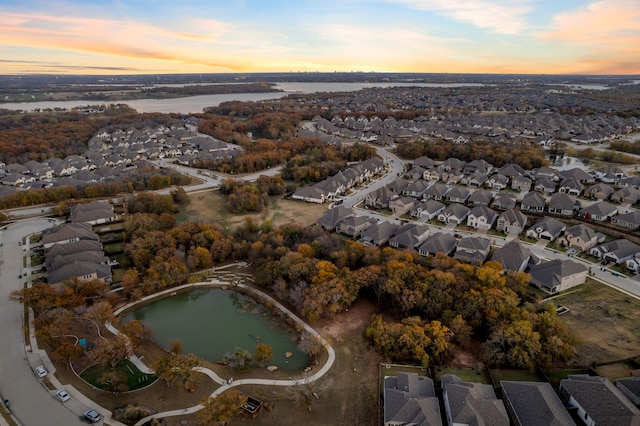 aerial view at dusk featuring a water view