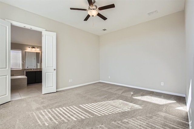 unfurnished bedroom with ensuite bathroom, ceiling fan, and light carpet