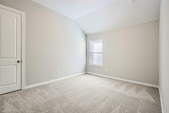 spare room featuring carpet flooring and vaulted ceiling