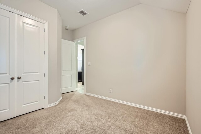 unfurnished bedroom featuring light carpet and a closet