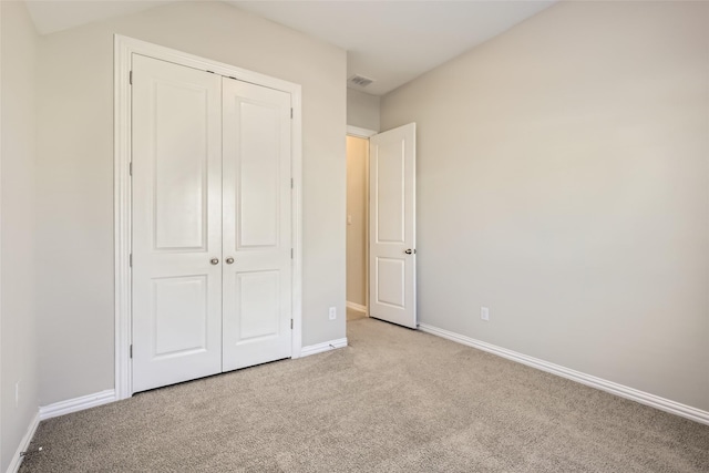 unfurnished bedroom featuring light carpet and a closet