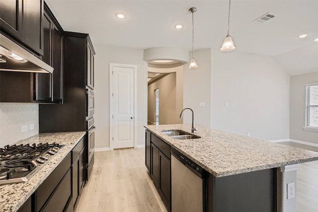 kitchen featuring a center island with sink, sink, light hardwood / wood-style flooring, decorative light fixtures, and stainless steel appliances