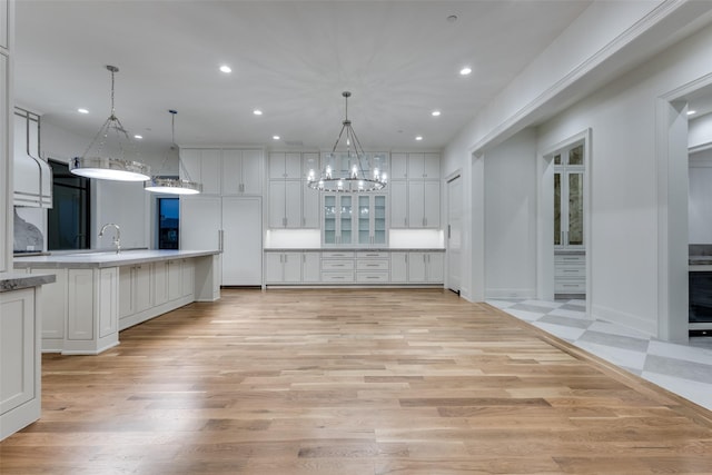 kitchen with light hardwood / wood-style flooring, a chandelier, hanging light fixtures, and white cabinets