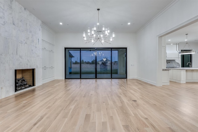 unfurnished living room featuring a notable chandelier, crown molding, light hardwood / wood-style flooring, and a tile fireplace