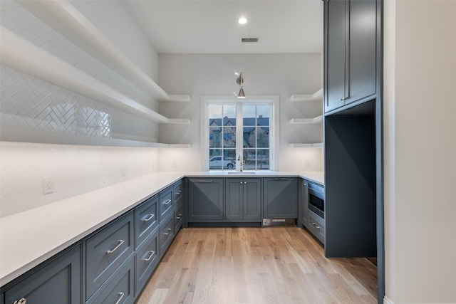 kitchen with oven, gray cabinets, sink, and light hardwood / wood-style flooring