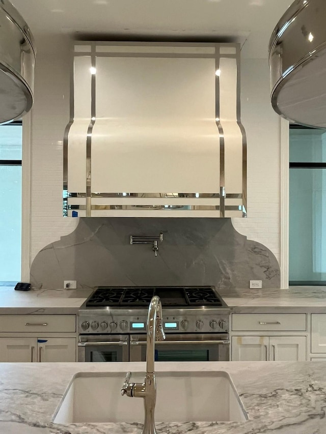 kitchen with backsplash, white cabinets, and range with two ovens