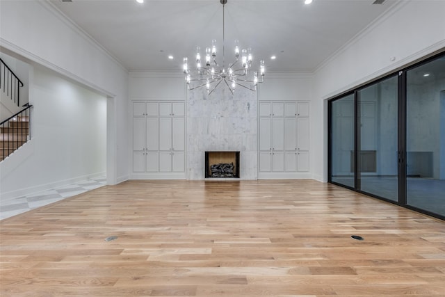 unfurnished living room with ornamental molding, a fireplace, a chandelier, and light wood-type flooring