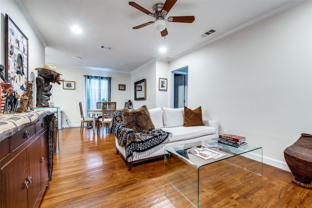 living room with light hardwood / wood-style floors, ceiling fan, and ornamental molding