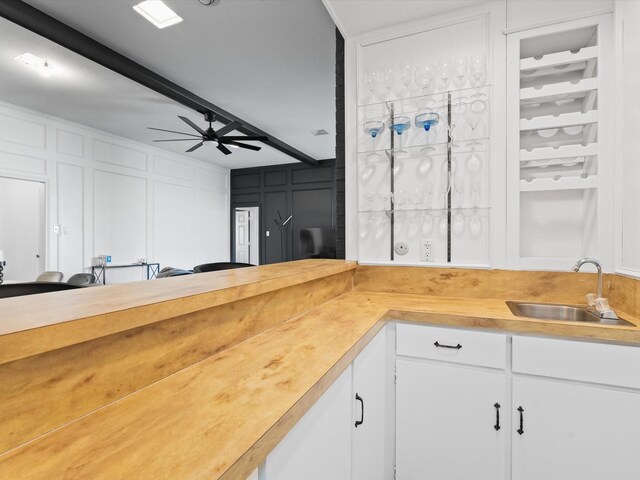 kitchen featuring white cabinets, beam ceiling, ceiling fan, and sink