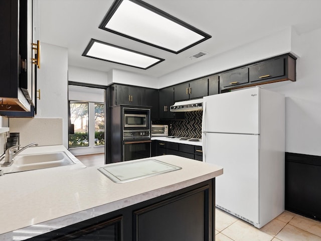 kitchen featuring light tile patterned flooring, stainless steel microwave, sink, black oven, and white fridge