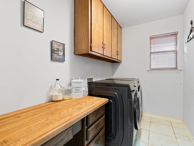 laundry room featuring cabinets, light tile patterned floors, and washer and clothes dryer